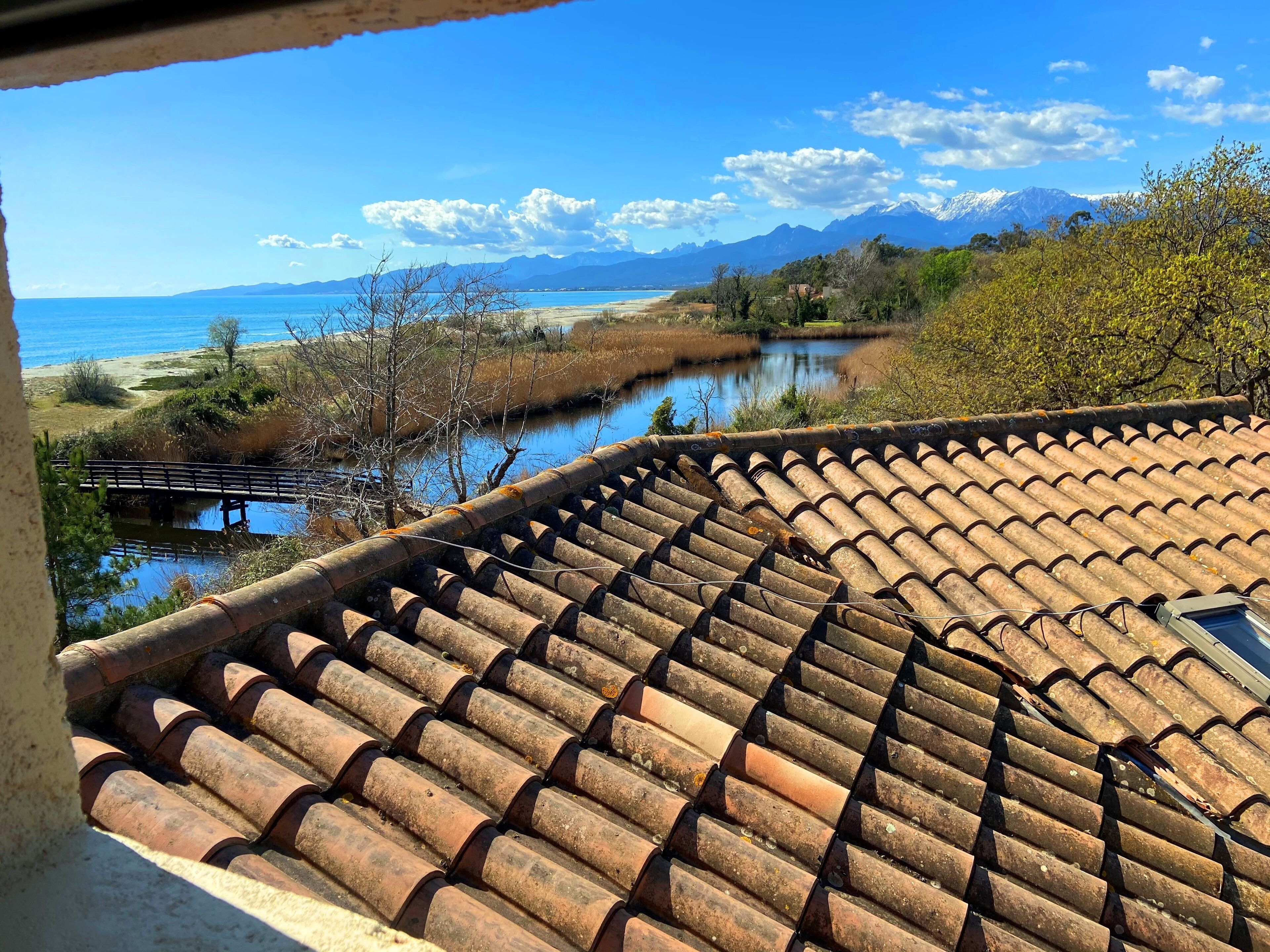 A tiled roof overlooking a river, a bridge, and distant mountains.