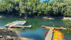 A dock with kayaks and small boats, surrounded by a forested area and a calm body of water. - Standing Apartment, Facing the Sea! (Ghisonaccia)