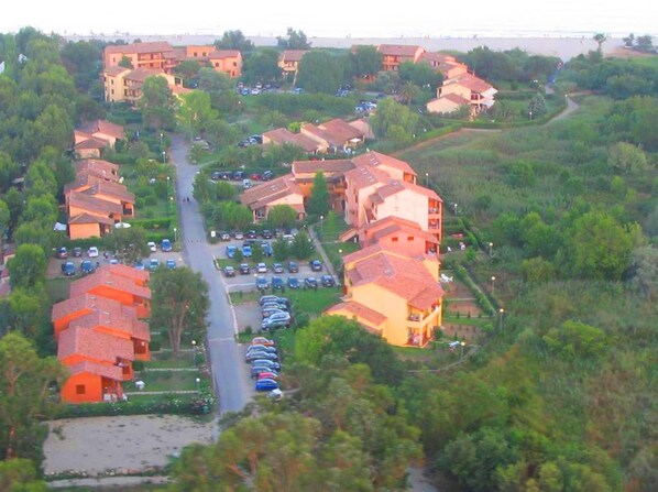 An aerial view of a residential area with multiple buildings, a central road, and parked cars. - Standing Apartment, Facing the Sea! (Ghisonaccia)