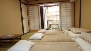 Une pièce de style japonais traditionnel, avec un sol recouvert de tatamis, une table basse et des futons servant de lits.