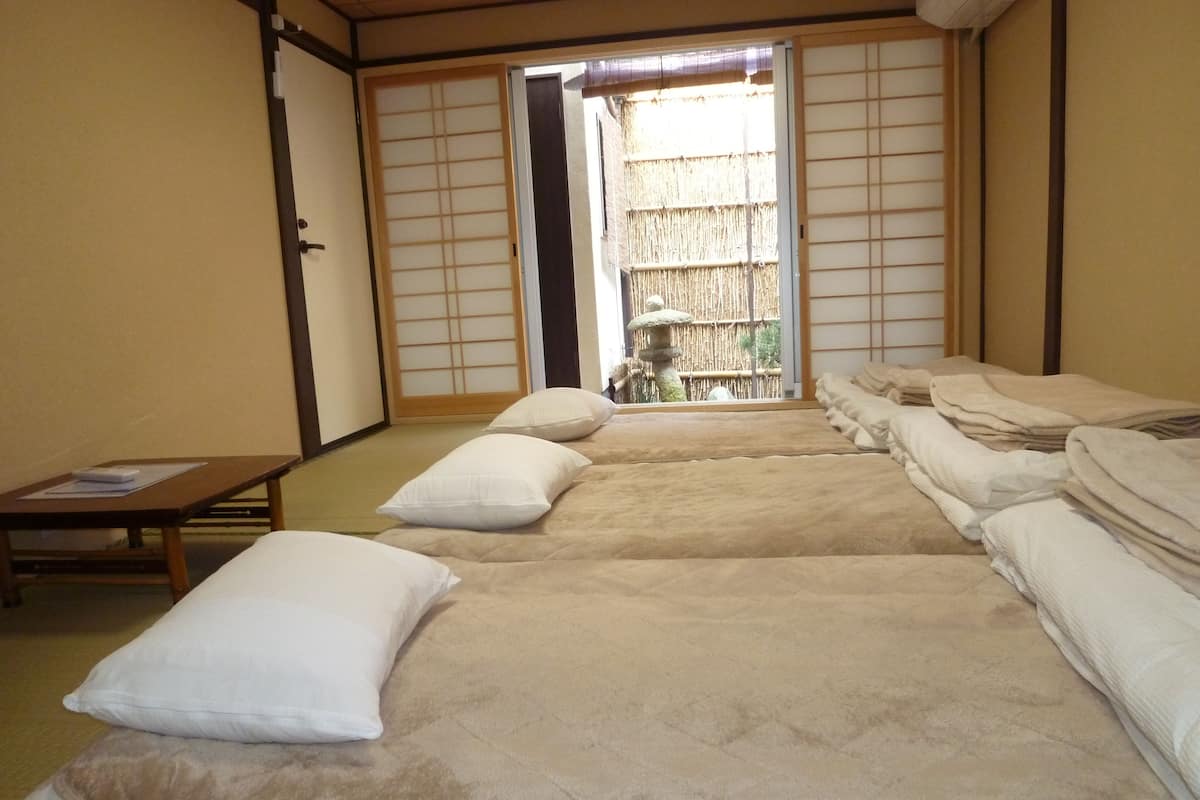 A traditional Japanese room with tatami flooring, a low table, and futon beds.