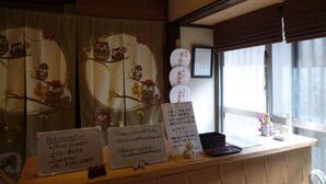 Un comptoir de réception d’hôtel avec une pancarte indiquant le service de réception, les numéros de téléphone et les coordonnées en cas d’urgence.