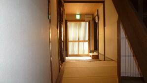 Un intérieur japonais traditionnel avec un sol recouvert de tatamis, une porte coulissante et un escalier.