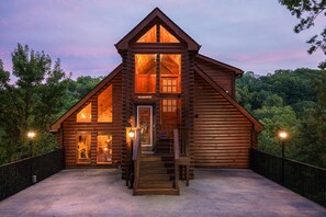 Una baita di legno con un ingresso accogliente, una scala che conduce al piano principale e vista sulla foresta circostante.