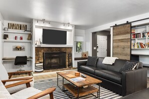 Ein modernes Wohnzimmer mit Kamin, einer schwarzen Ledersofa, einem Holztisch und einem Bücherregal.