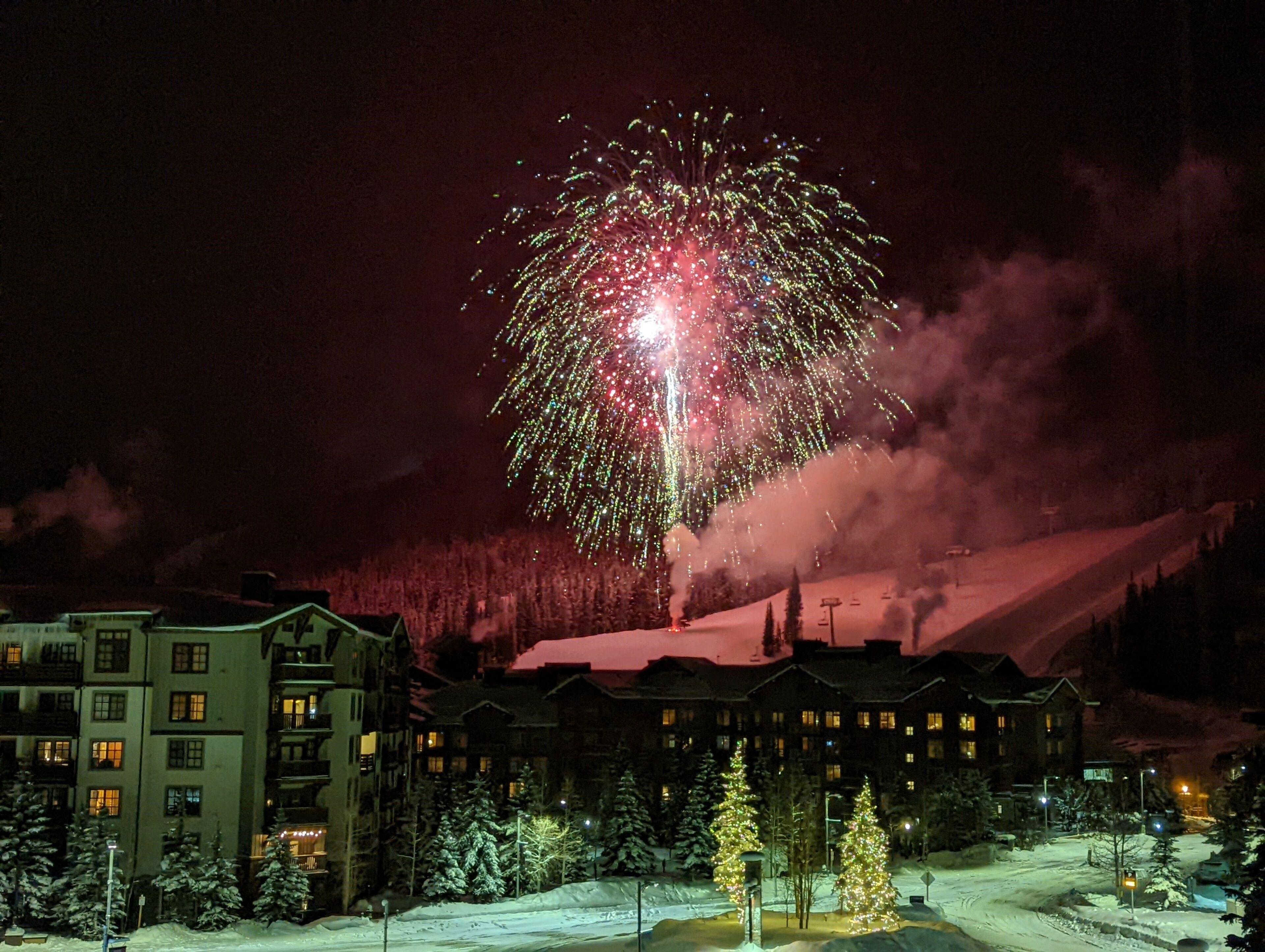 Ein Hotel mit mehreren Etagen, verschneiter Umgebung und Blick auf einen schneebedeckten Berg im Hintergrund.