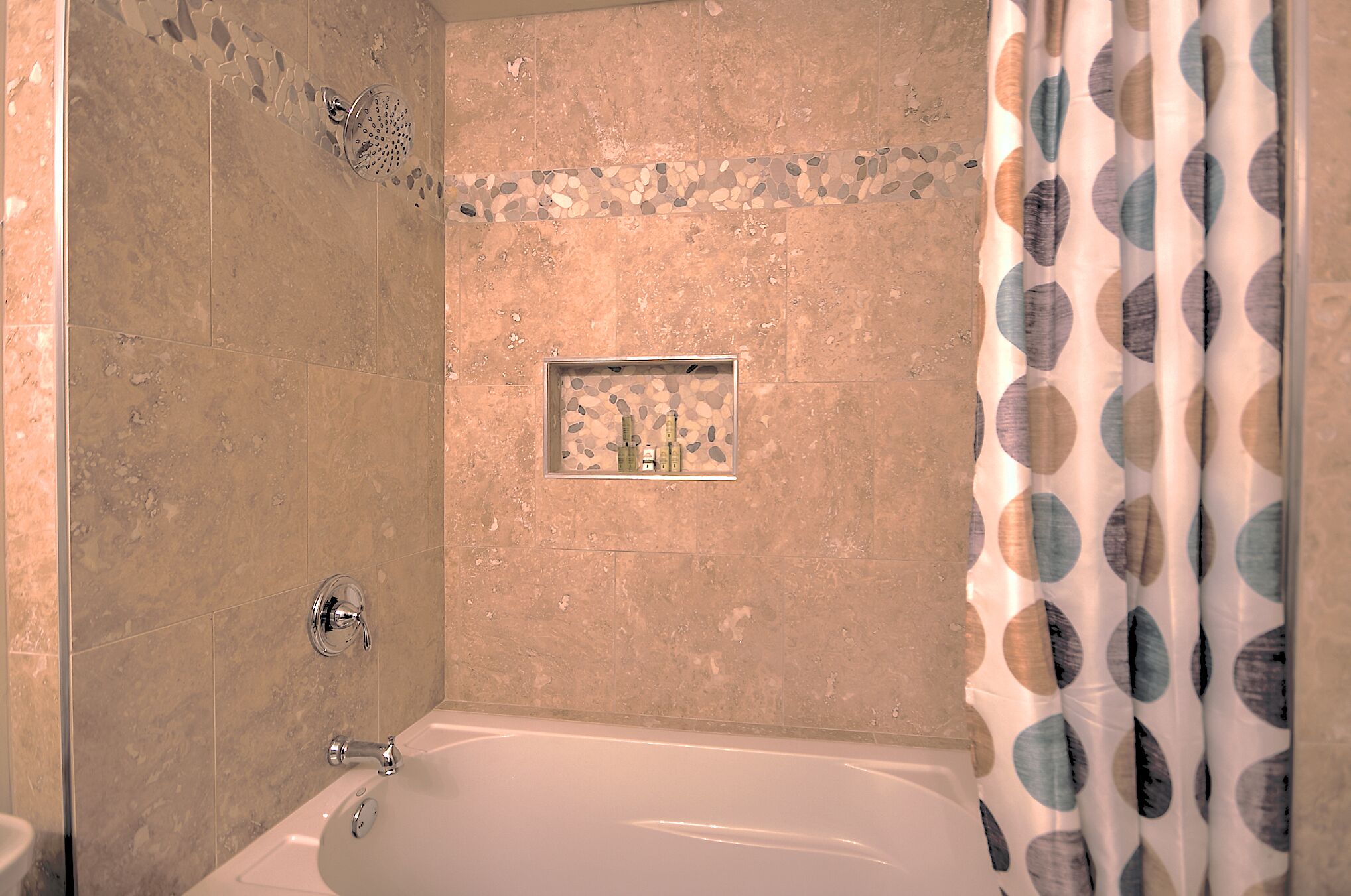 Une salle de bain avec une baignoire, une douche et un mur décoré de carreaux.