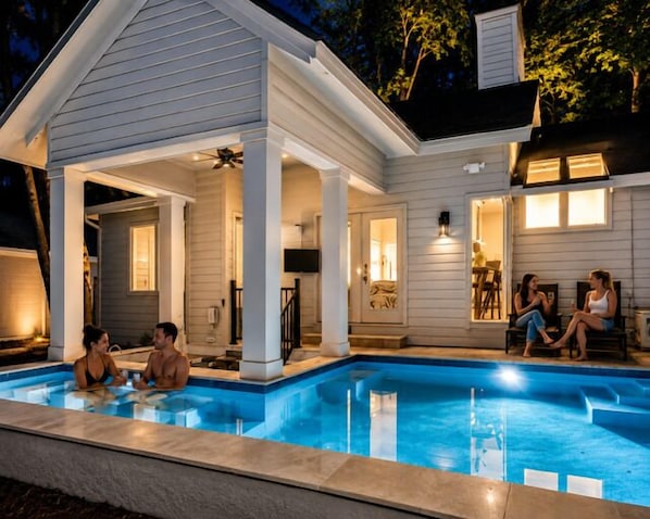 A swimming pool with a covered area, a dining area, and a kitchen visible.