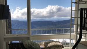 A room with a large window overlooking a mountainous landscape. - Twin Towers 701A (Mount Buller)