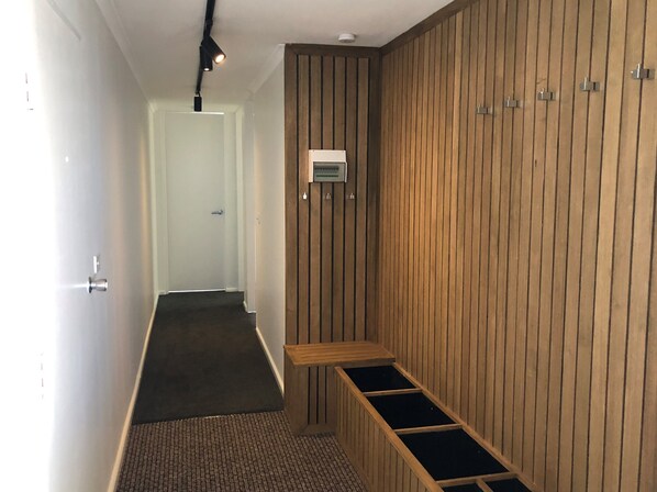 A hallway with a wooden wall, a bench, and a door at the end.