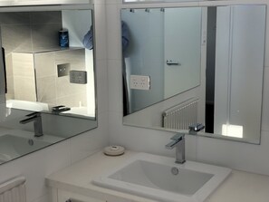 A modern bathroom with a white sink, a mirror, and a shower area. - Twin Towers 701A (Mount Buller)