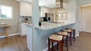 A modern kitchen with white cabinets, a granite countertop, and a built-in island with bar stools.