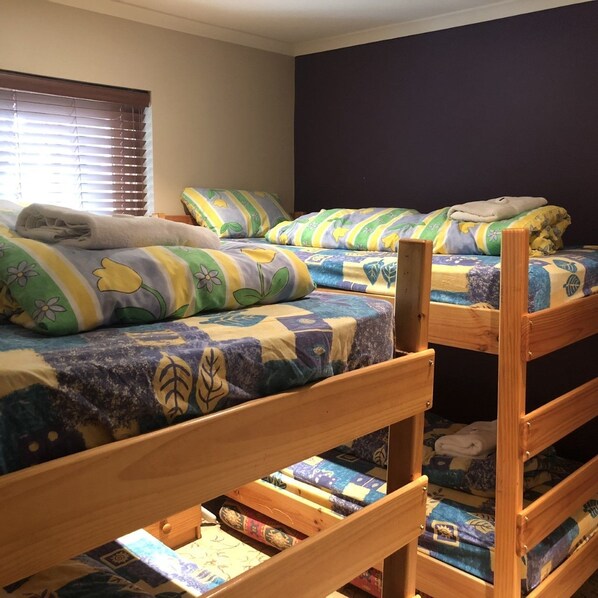 A room with two bunk beds, each with a patterned bedspread and pillows.