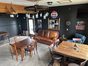 A dining area with a wooden table and chairs, a leather couch, and a dartboard.