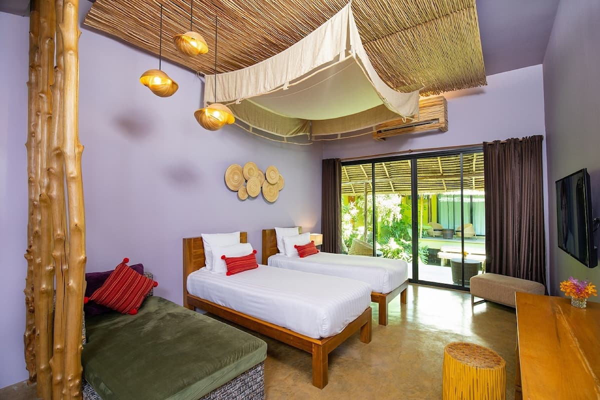 A room with two beds, a wooden bench, a small table, and a TV.