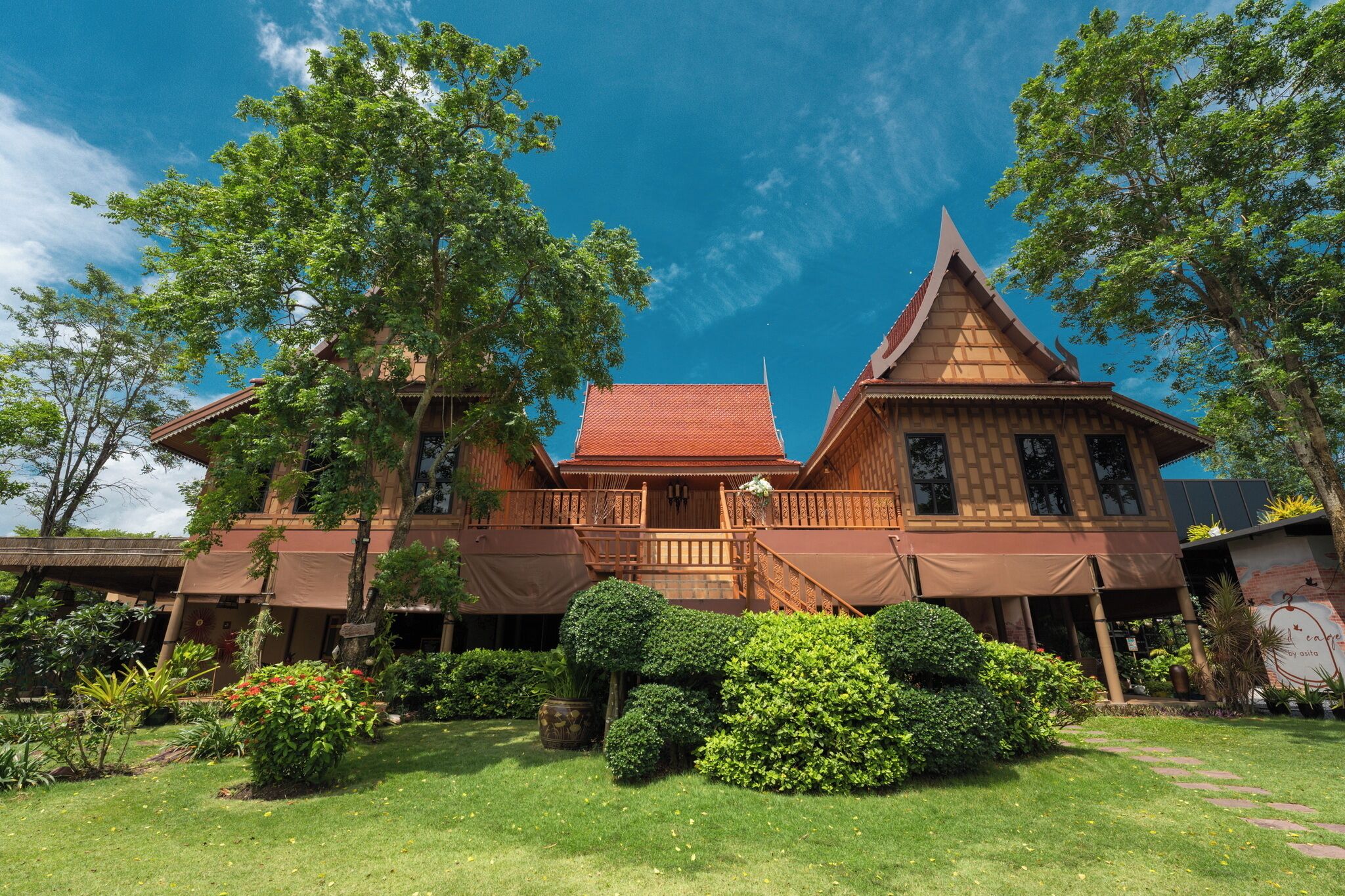 A traditional wooden building with a red roof, surrounded by lush greenery and trees.