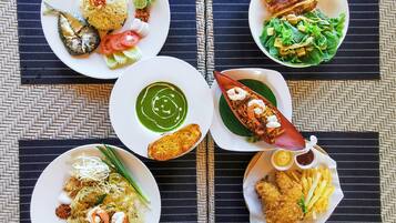 A table with various dishes including rice, fish, and fried items, set on a woven placemat.