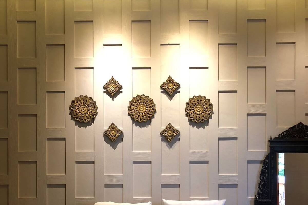A hotel room with a bed, decorative wall panels, and a mirror.