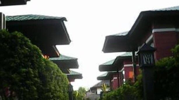A pathway leading to traditional buildings with green roofs and red walls. - Pyi1 Guest House (Nyaungshwe)