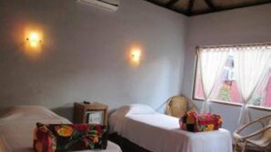 A room with two beds, a chair, and a window with curtains. - Pyi1 Guest House (Nyaungshwe)