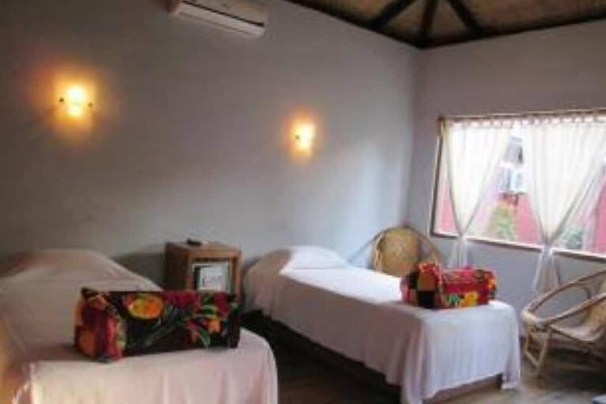 A room with two beds, a chair, and a window with curtains.