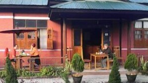 A building with a red facade and a covered outdoor seating area with tables and chairs. - Pyi1 Guest House (Nyaungshwe)