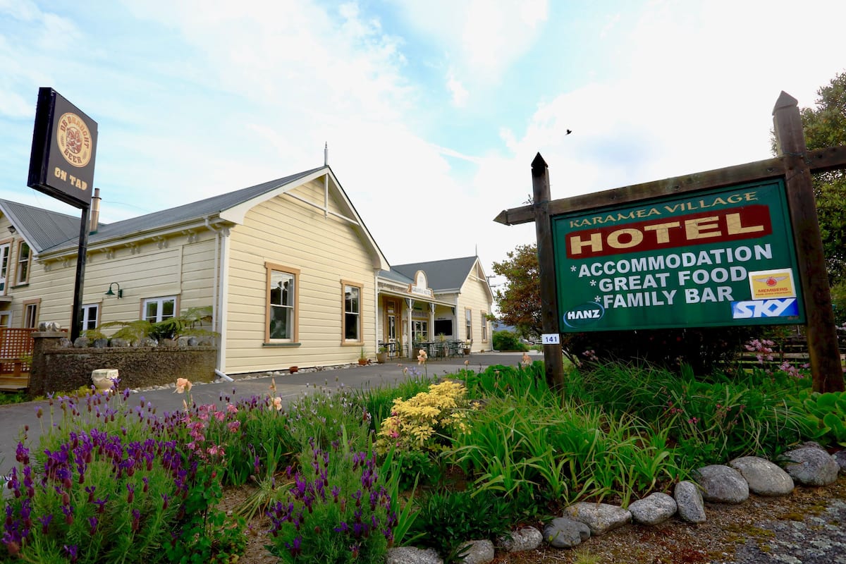 Une enseigne d’hôtel indiquant « Karamere Village Hotel », et proposant des services tels que l’hébergement, une excellente cuisine et un bar familial.