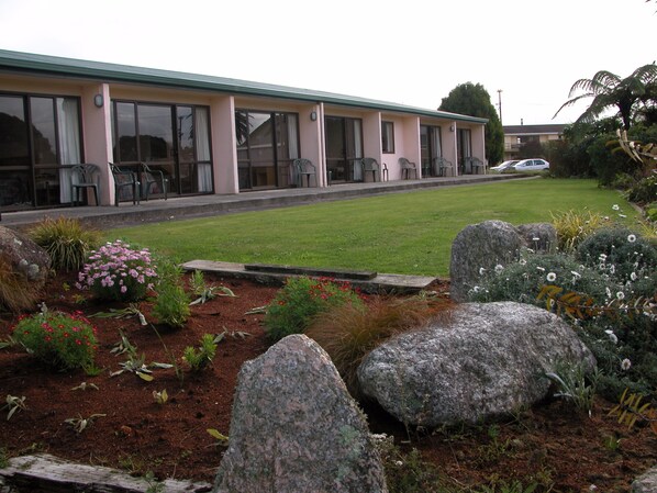 A building with a flat roof, large windows, and a paved driveway. - Karamea Hotel (Karamea)