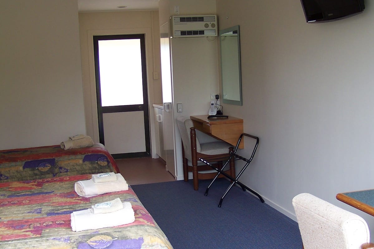Une chambre d’hôtel équipée d’un grand lit, d’un bureau, d’une chaise, d’un téléviseur à écran plat et d’un système de climatisation.
