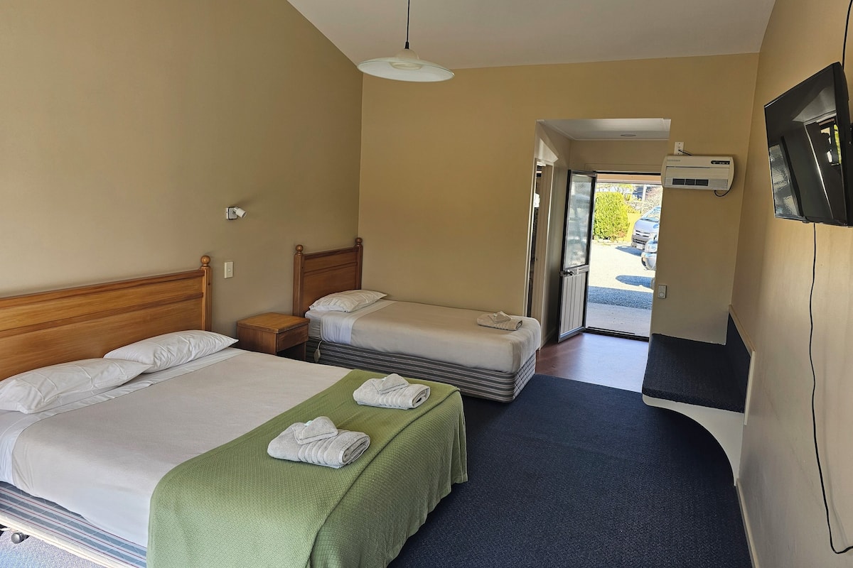 Une chambre d’hôtel avec deux lits, une télévision, un appareil de climatisation et une vue sur l’extérieur.