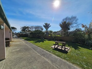 A backyard with a concrete pathway, a wooden bench, and a picnic table.