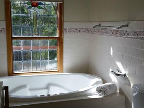 A bathroom with a bathtub, a window, and a toilet. - Day Dream Cottage (Merrijig)