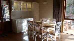 Een moderne keuken met witte kasten en een eethoek met witte stoelen.