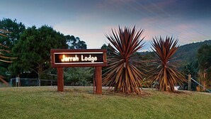 A sign for Jerrah Lodge with a backdrop of a sunset and agave plants. - Jarrah Lodge (Merrijig)