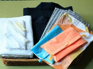 A basket containing neatly folded towels and a toothbrush. - Aso No Shiki (Aso)