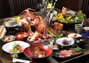 A variety of dishes including seafood, vegetables, and meats, arranged on a wooden table with a traditional setting. - Aso No Shiki (Aso)