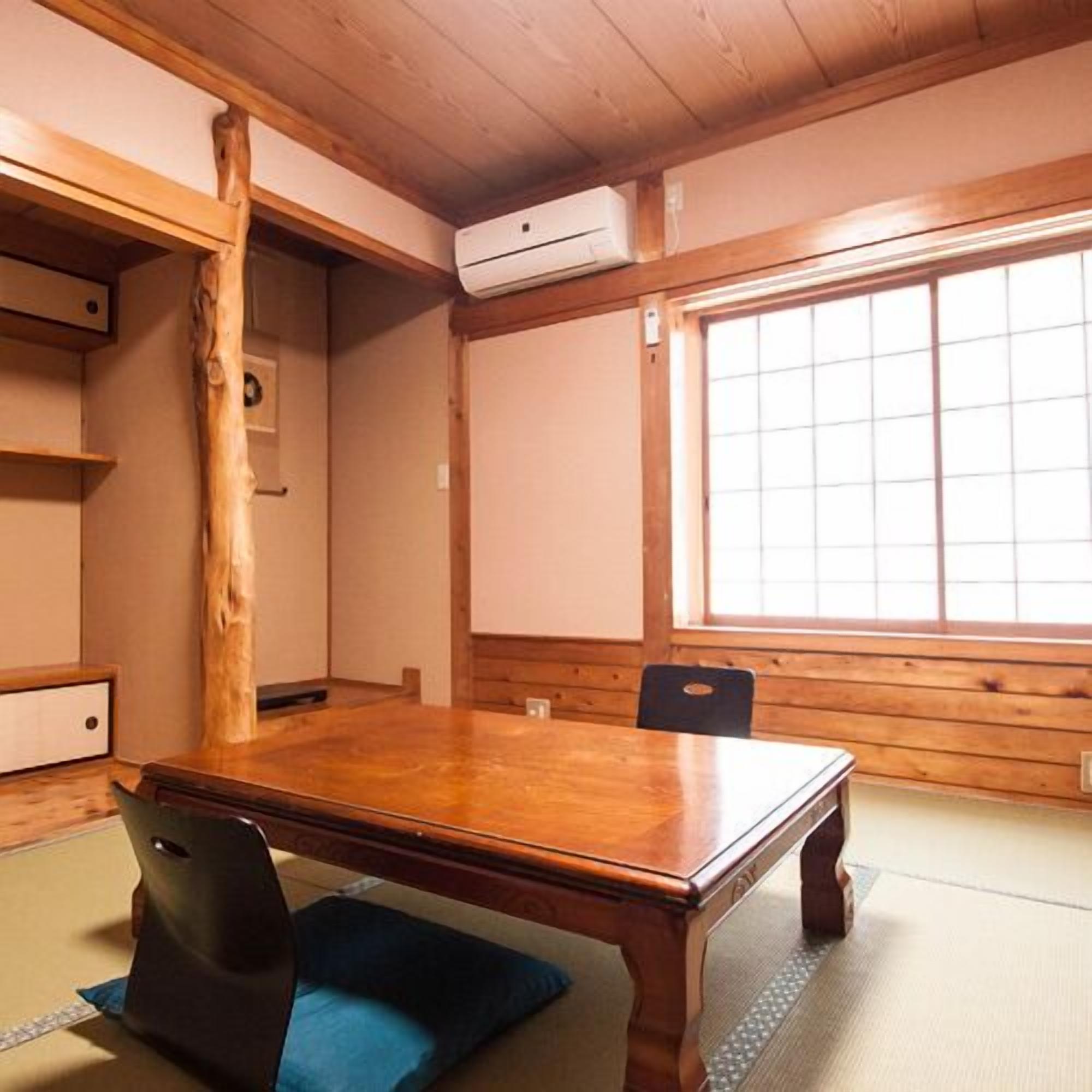 Una habitación tradicional japonesa con suelo de tatami, una mesa de madera y una puerta corredera.