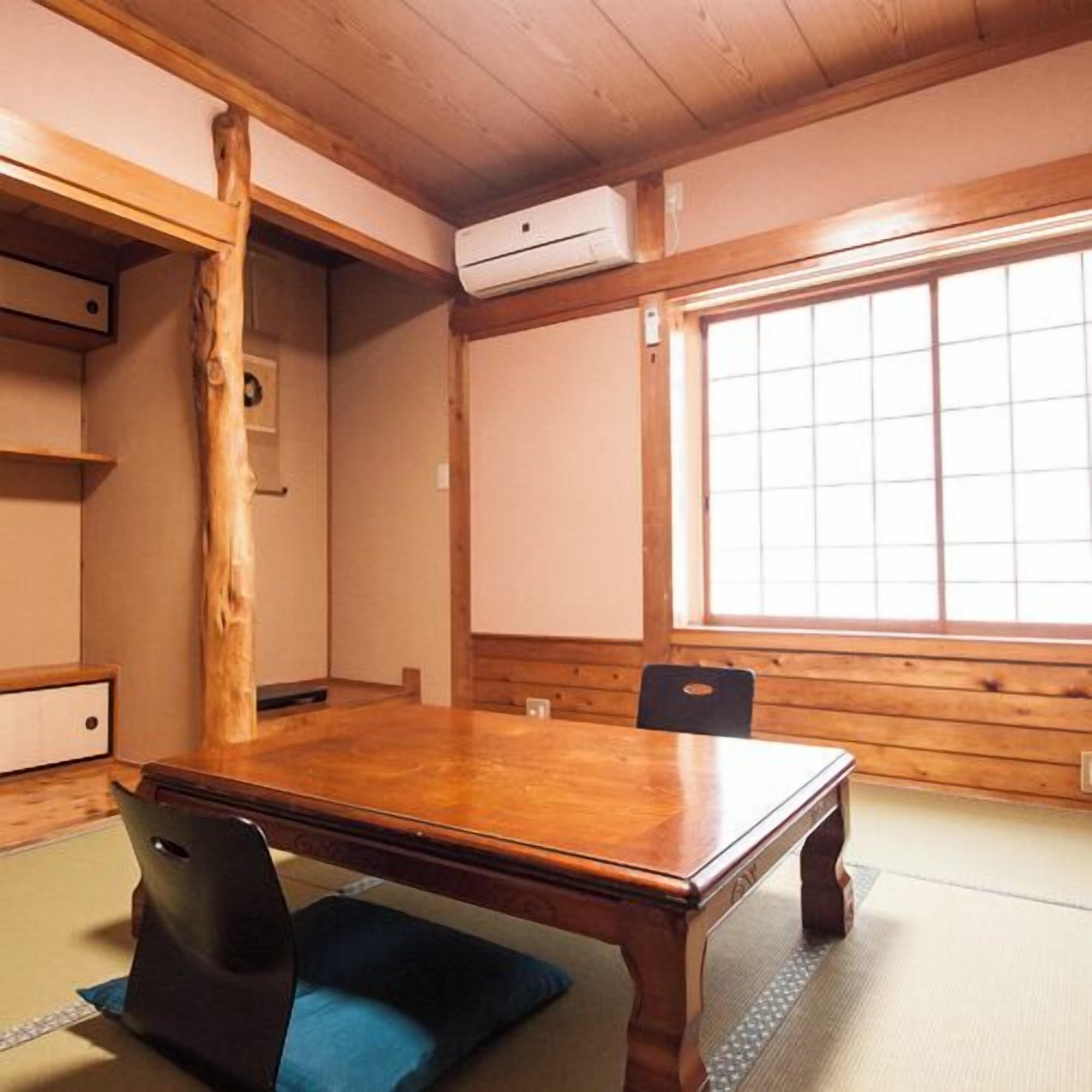 Una habitación tradicional japonesa con suelo de tatami, una mesa de madera y un puertas correderas.