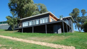 A modern house with a flat roof, large windows, and a covered outdoor area.
