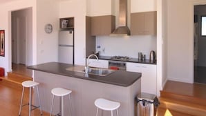 A modern kitchen with a central island, bar stools, and a built-in oven.