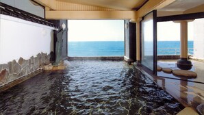 A spa area with a view of the ocean, stone walls, and a wooden ceiling. - Hotel Yaotome (Tsuruoka)