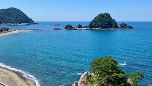 A coastal scene with clear blue waters, a sandy beach, and rocky islands. - Hotel Yaotome (Tsuruoka)