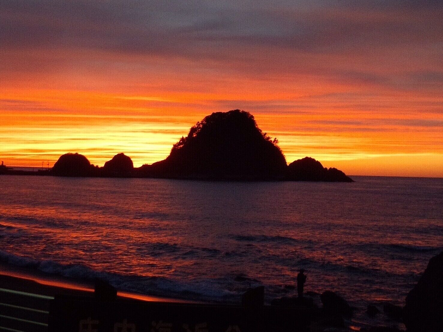 Un atardecer sobre un mar tranquilo con varias islas pequeñas silueteadas contra el cielo.