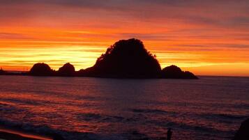 Un atardecer sobre un mar tranquilo con varias islas pequeñas silueteadas contra el cielo.
