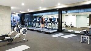 A gym with various cardio machines, a rowing machine, and a treadmill. - C3CBD Melbourne Apartment (Melbourne)