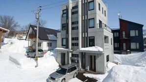 A multi-story building with a modern architectural design, featuring a mix of residential and commercial spaces. - Udelka A (Kutchan)