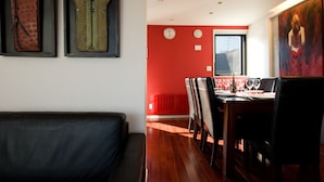 A modern dining area with a red accent wall, wooden flooring, and a dining table set for four. - Udelka A (Kutchan)