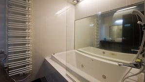A modern bathroom with a glass-enclosed bathtub, a white towel rack, and a visible showerhead. - Udelka A (Kutchan)