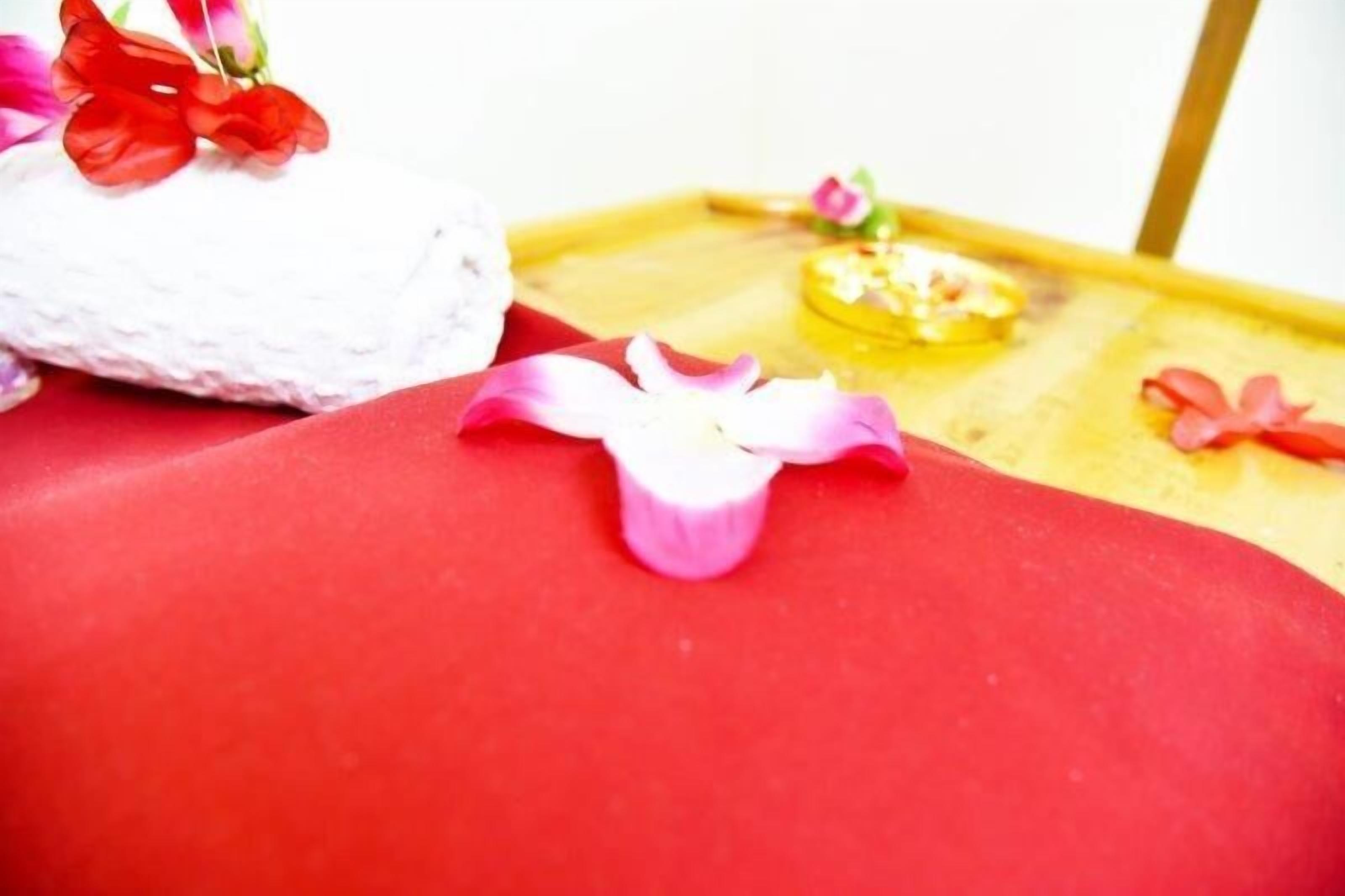 A red cushioned surface with a white textured object and a small yellow tray with a pink flower.