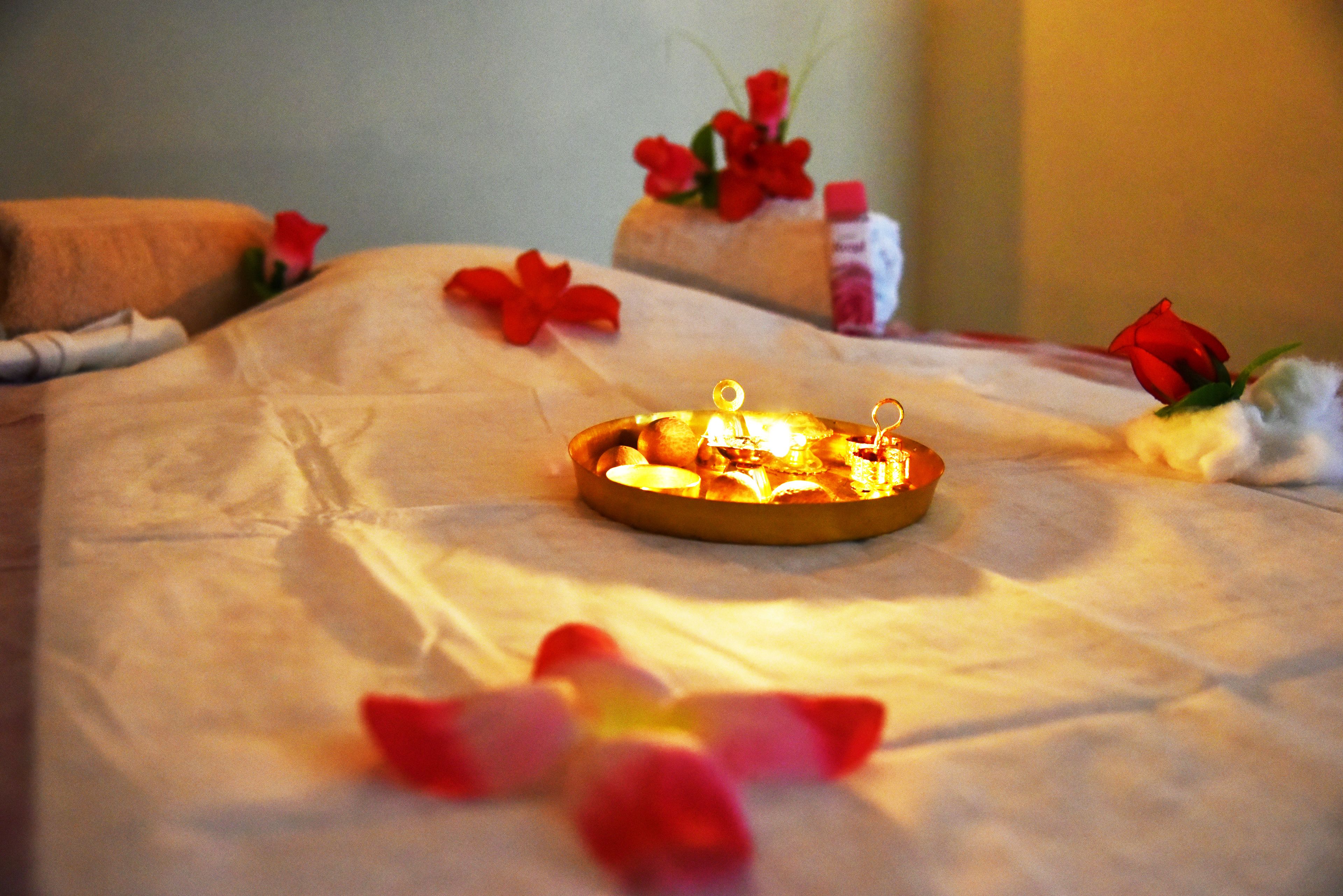 A neatly made bed with a tray of food and flowers, suggesting a hotel room setting.